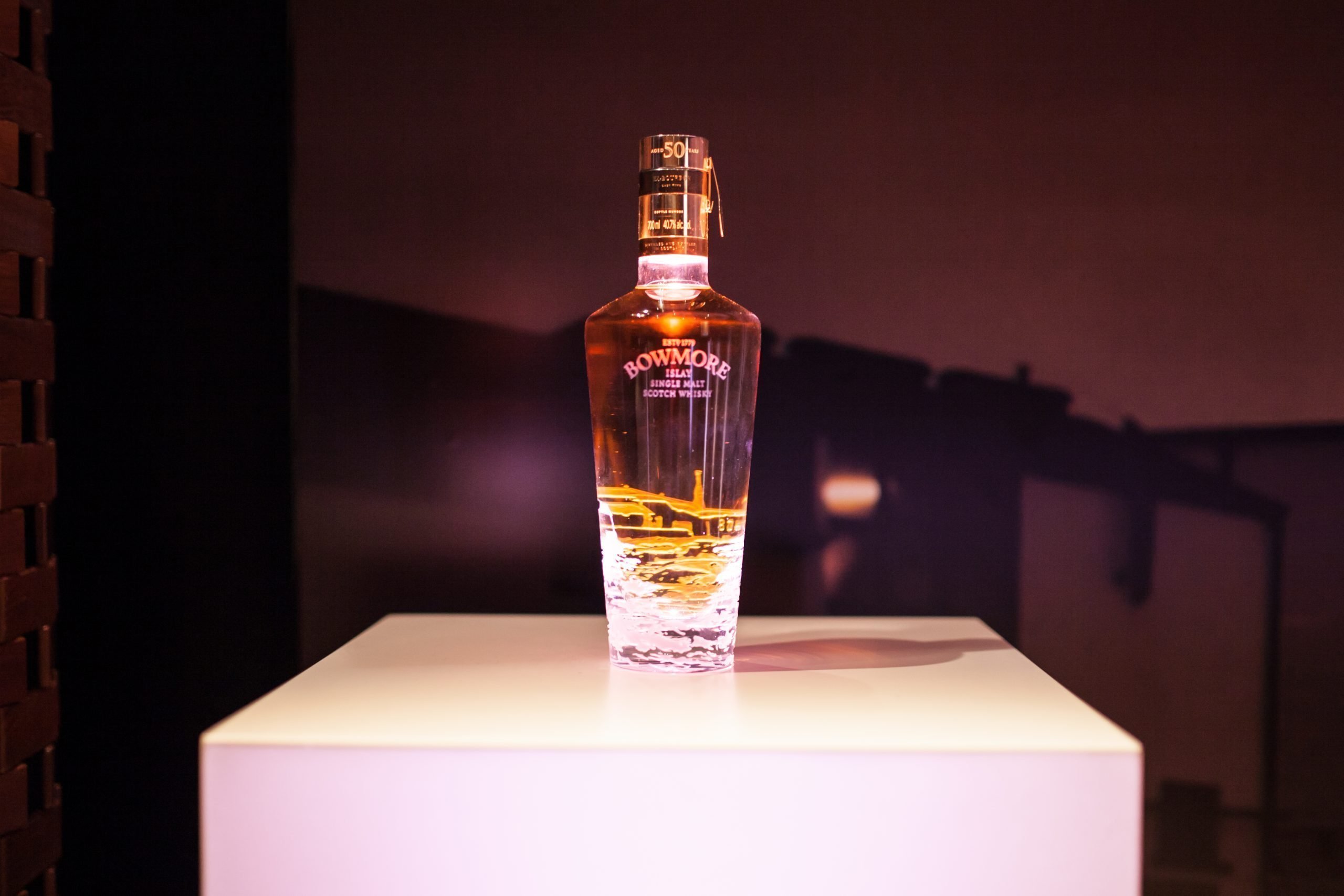 Lit whisky bottle on white plinth