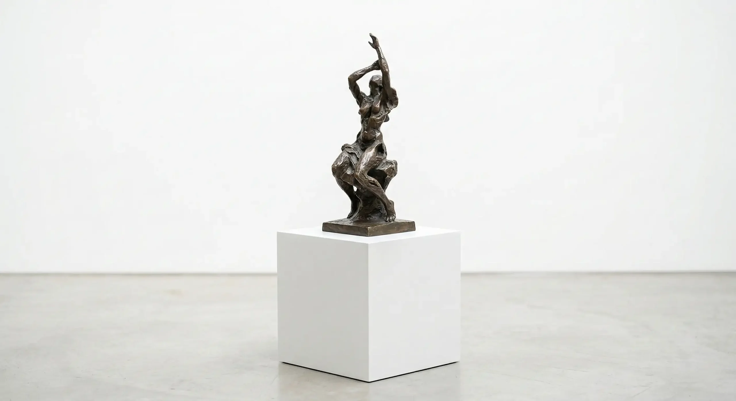 Minimalist white spray-finished art plinth with a bronze figurative sculpture on a seamless gallery background