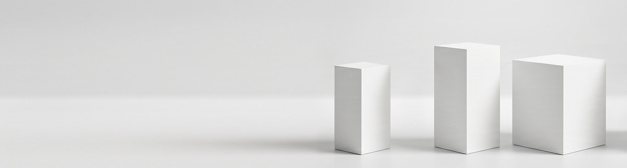 A staggered arrangement of four matte white standard display plinths on a seamless light grey background, handcrafted by Exhibition Plinths UK